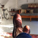 Brown Aurora Shoe Co. Middle English shoes on customer's feet, inside apartment with bicycle and futon in background. Warm light from an adjacent window highlights the patina of the brown leather shoes on the customers bare feet.