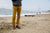 Man standing on sand, with golden gate bridge in background, wearing grey sweater, mustard yellow khaki pants, and brown North Pacific Handmade Leather Shoes