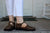 woman wearing T-strap Aurora Shoe Co. handmade leather shoes on wood porch.