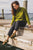 Woman sitting on dock at Cayuga Lake, wearing green shirt, black pants, and Olive Aurora Shoe Co. T-Strap leather shoes.