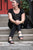 Woman sitting on stone steps, looking to side, wearing all black and black New Mexican handmade leather shoes by Aurora Shoe Co.