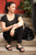 Woman sitting on stone steps, looking to other side, wearing all black and black New Mexican handmade leather shoes by Aurora Shoe Co.