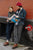 Couple stnading against brick wall, reading paper, both wearing brown North Pacific handmade leather boots by Aurora Shoe Co.